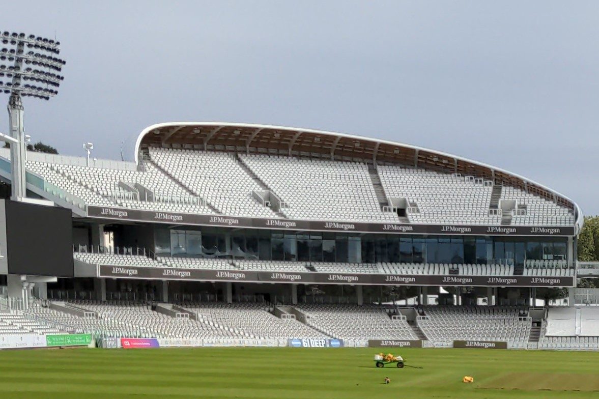 Three tiers of the Compton Stand at Lord’s beneath its curving roof, photographed across the field in October 2021